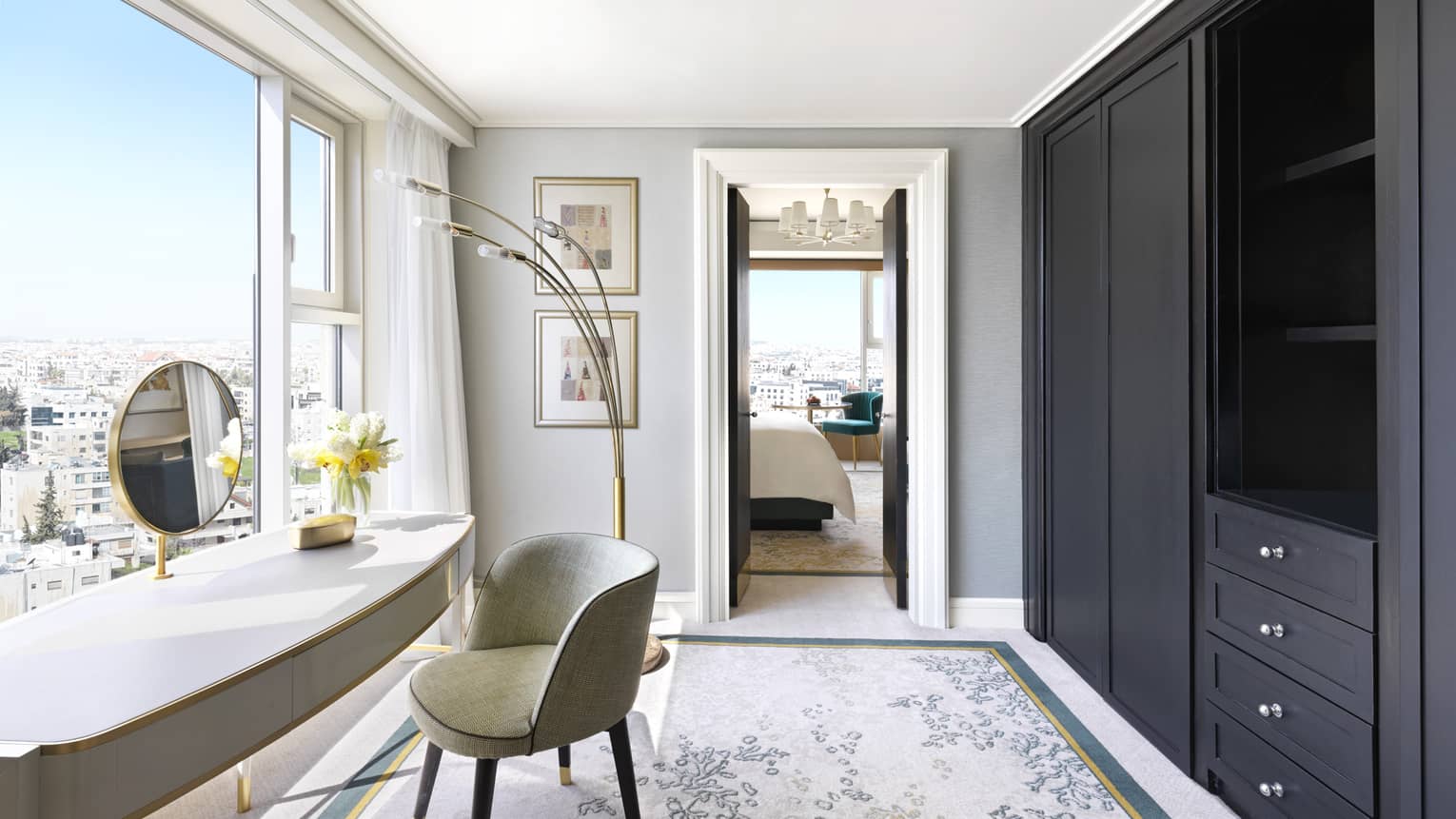 A small dressing room with a large black wardrobe overlooking the city.