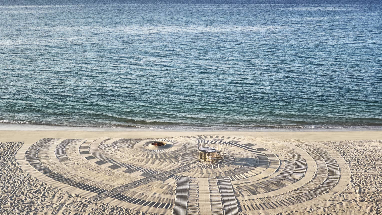 A dining table on a beach next to the water.
