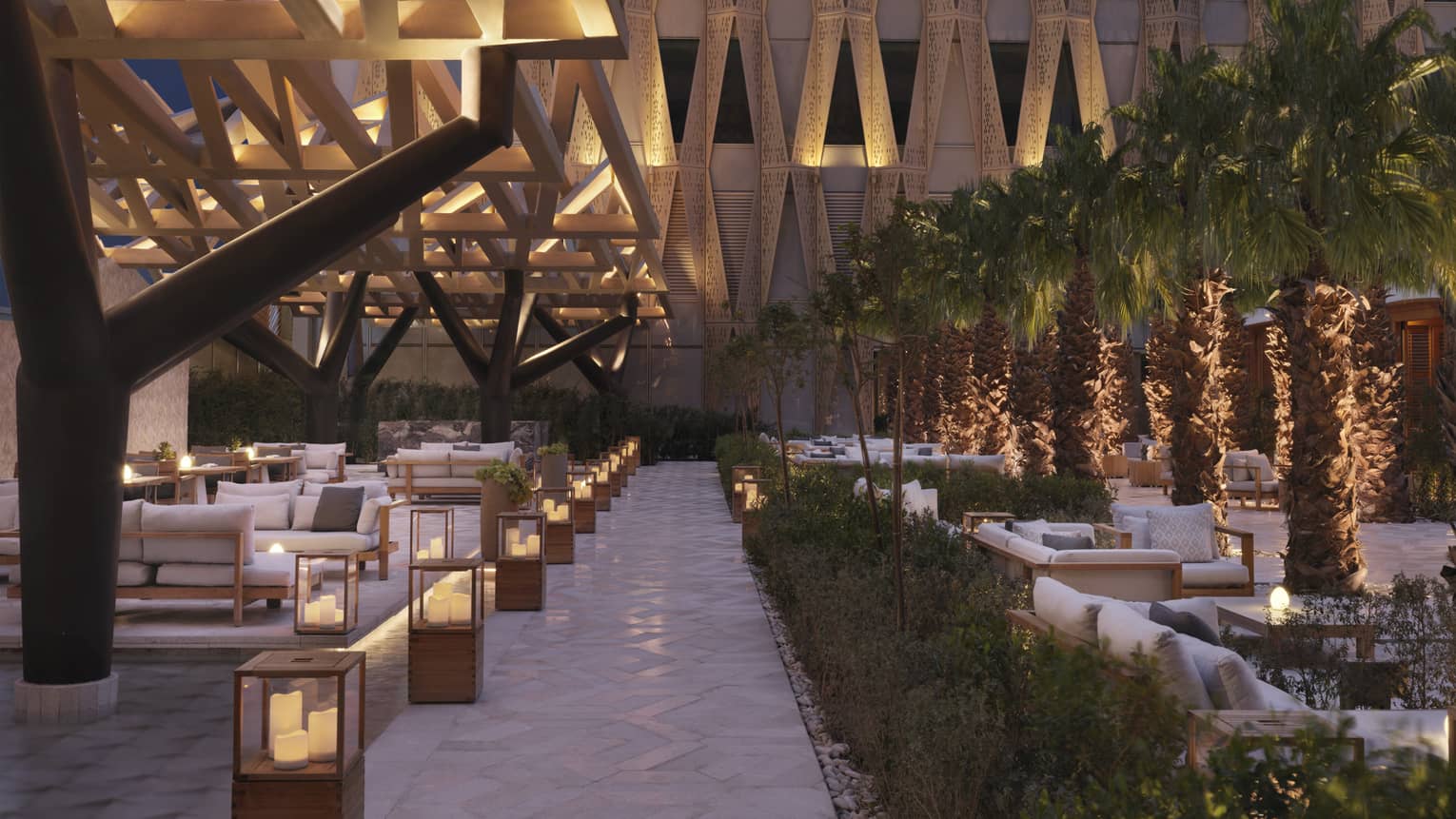 Illuminated outdoor patio sitting area with architectural designs on surround building.