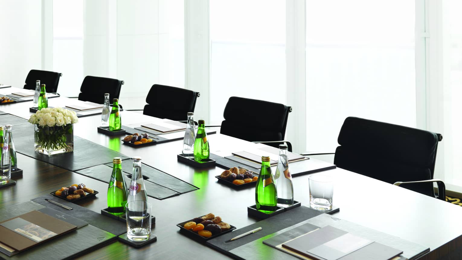 Boardroom meeting table set with water, dried apricots, menus by sunny window
