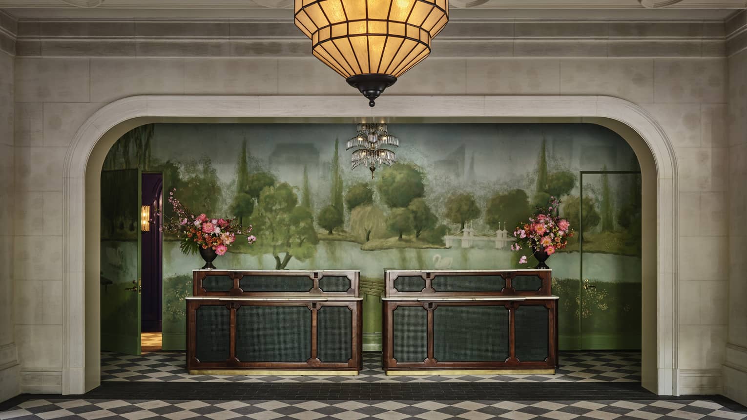 A colourful reception desk with flowers and paintings of trees behind it.