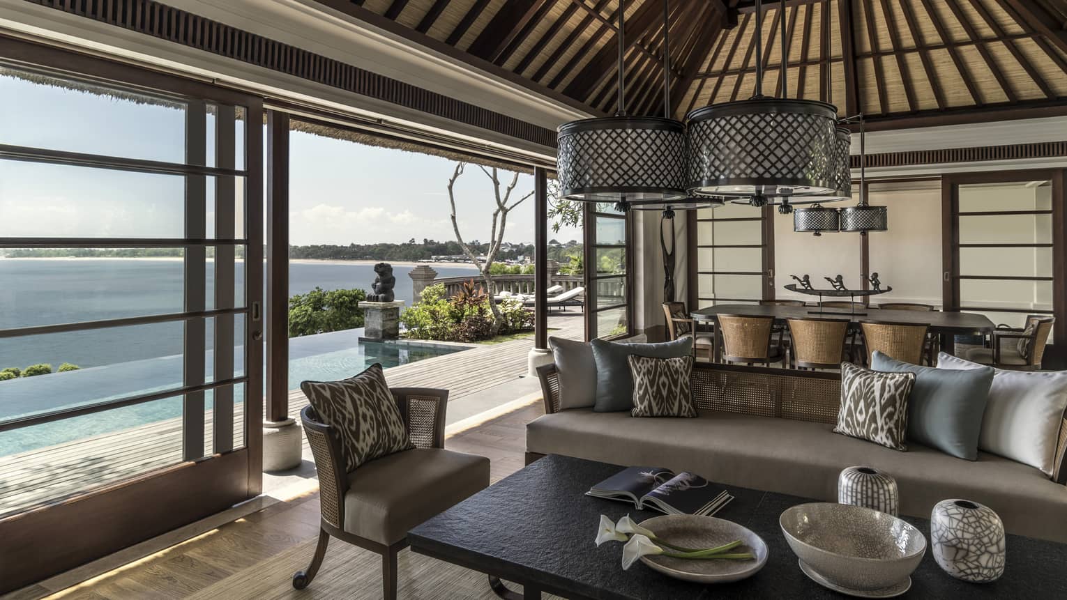 Royal Villa living room with beige sofas, round wicker chandeliers, sliding glass wall to sunny patio