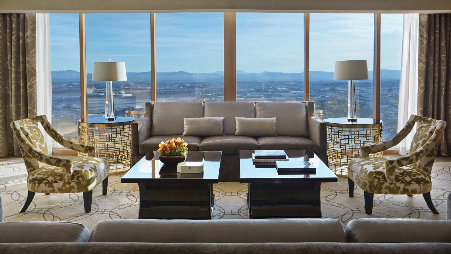 Valley-View Suite silver sofas, gold accent chairs, wall of windows with sweeping Las Vegas views