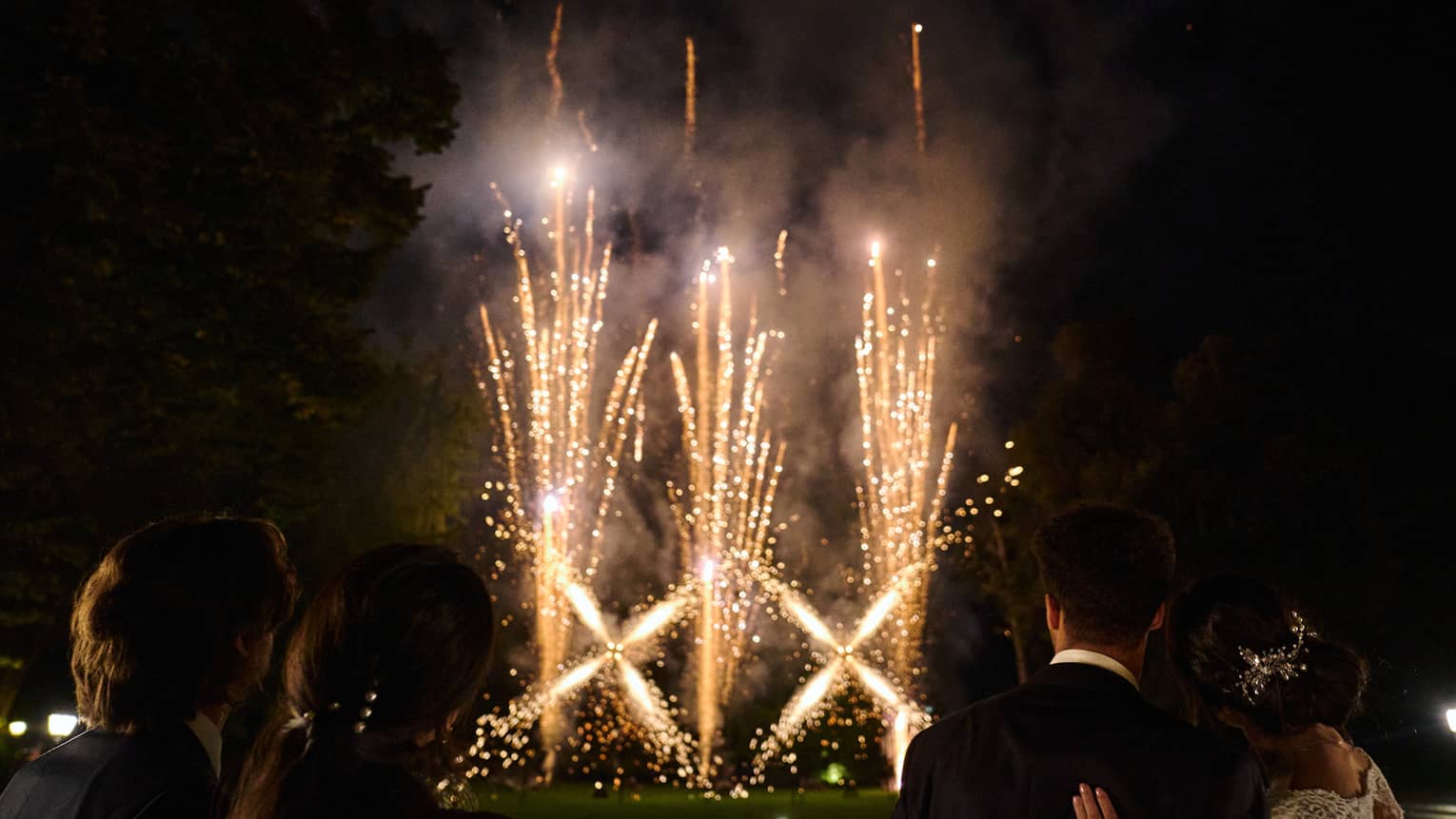 Vertical fireworks display with people looking on