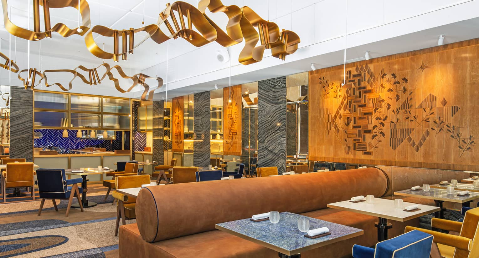 Modern dining area with gold, blue and deep camel accents and art flanking walls and ceiling