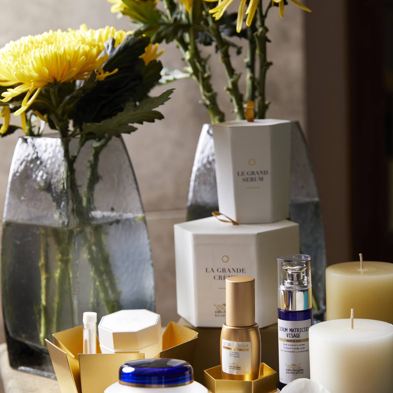 Cosmetics bottles on boxes next to yellow flowers on spa table