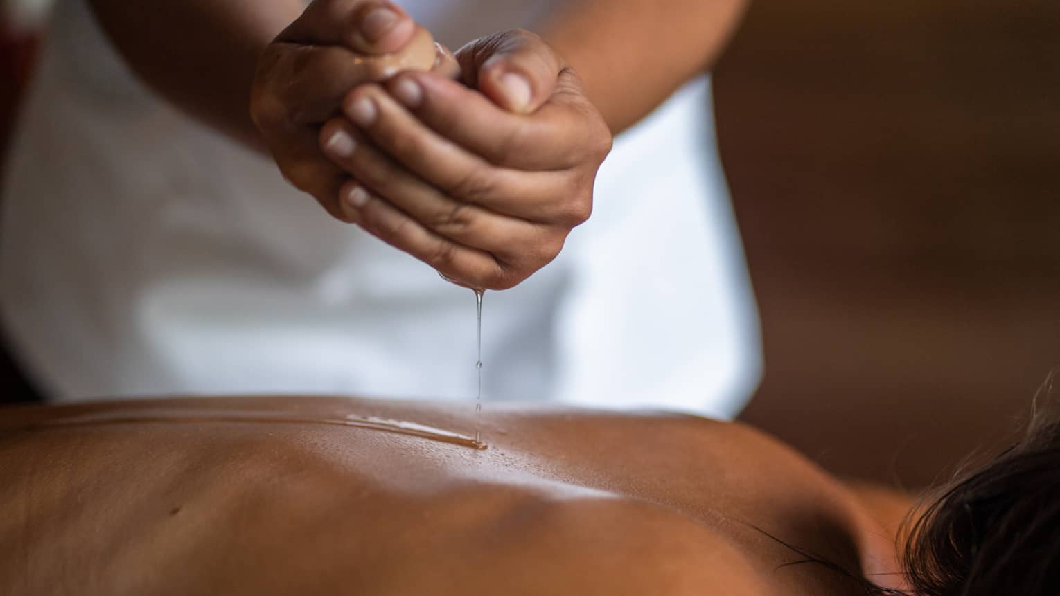 Delicate hands apply oil to a guest's back during a spa treatment