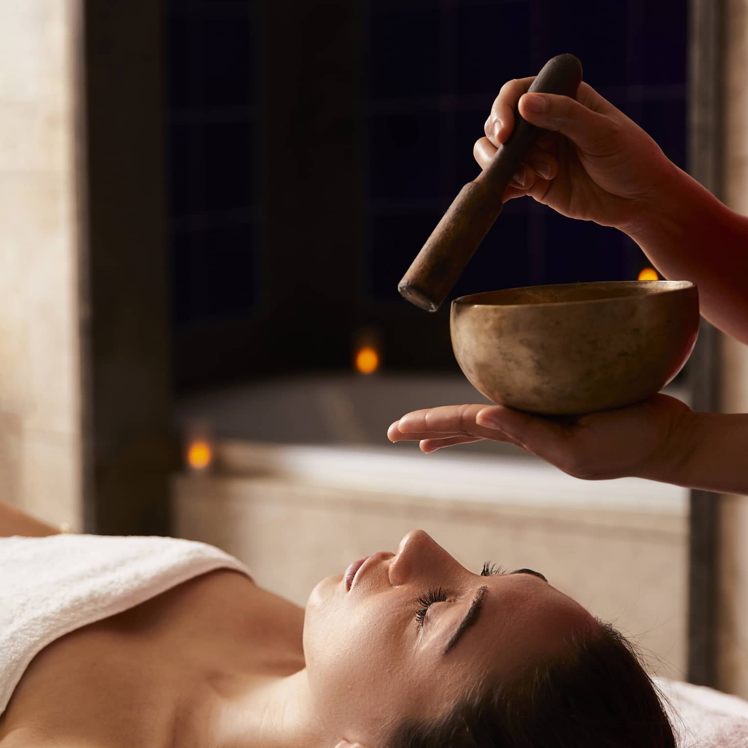 A woman receiving a spa treatment with bowls to create sounds.