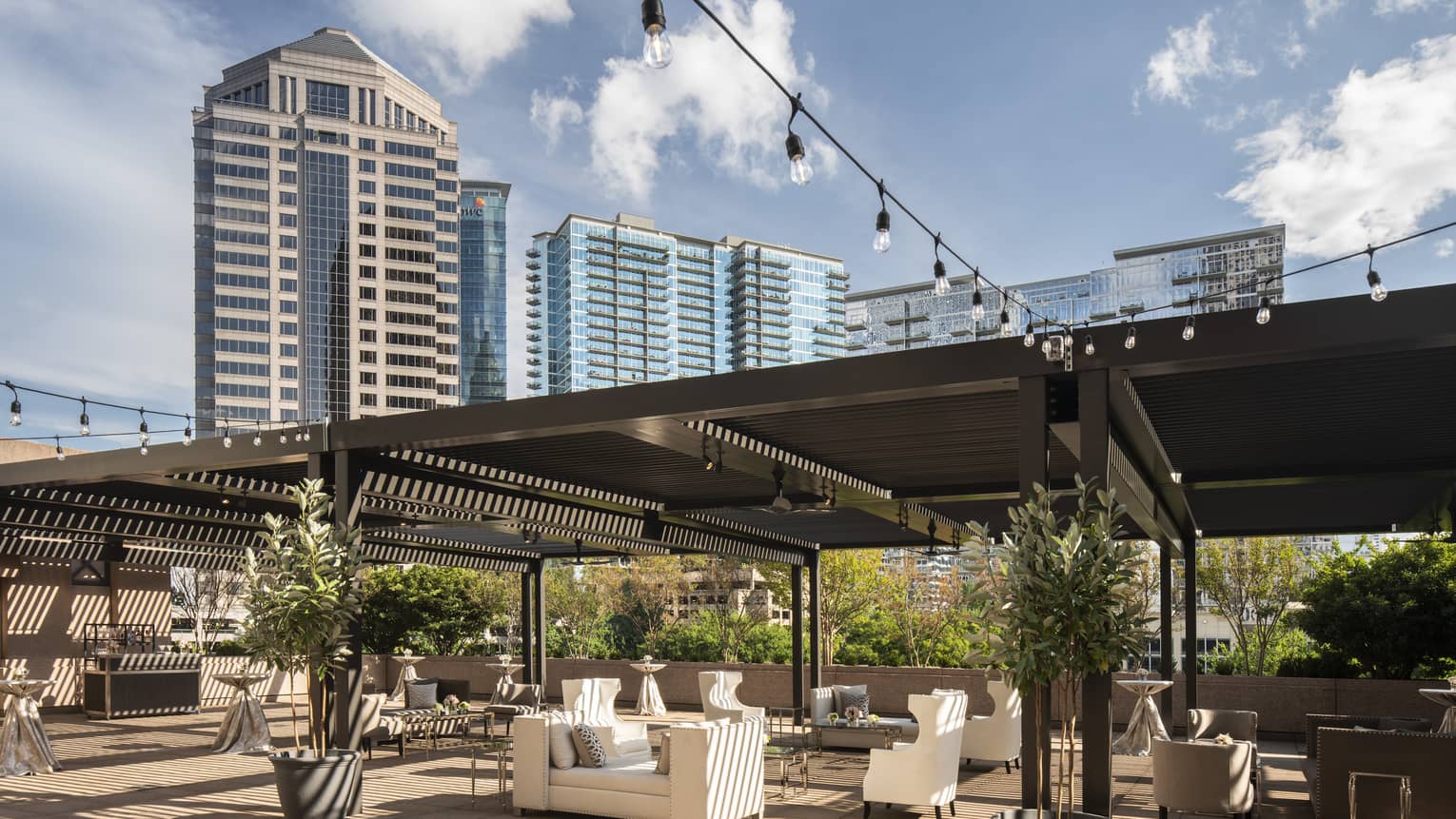 Fifth-floor rooftop terrace during the day with modern white sofas under large wood pergola
