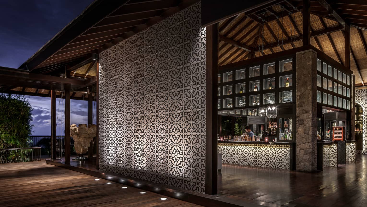 Bar interior, showing mosaic wall and mosaic lined bar with bartender and evening views out window