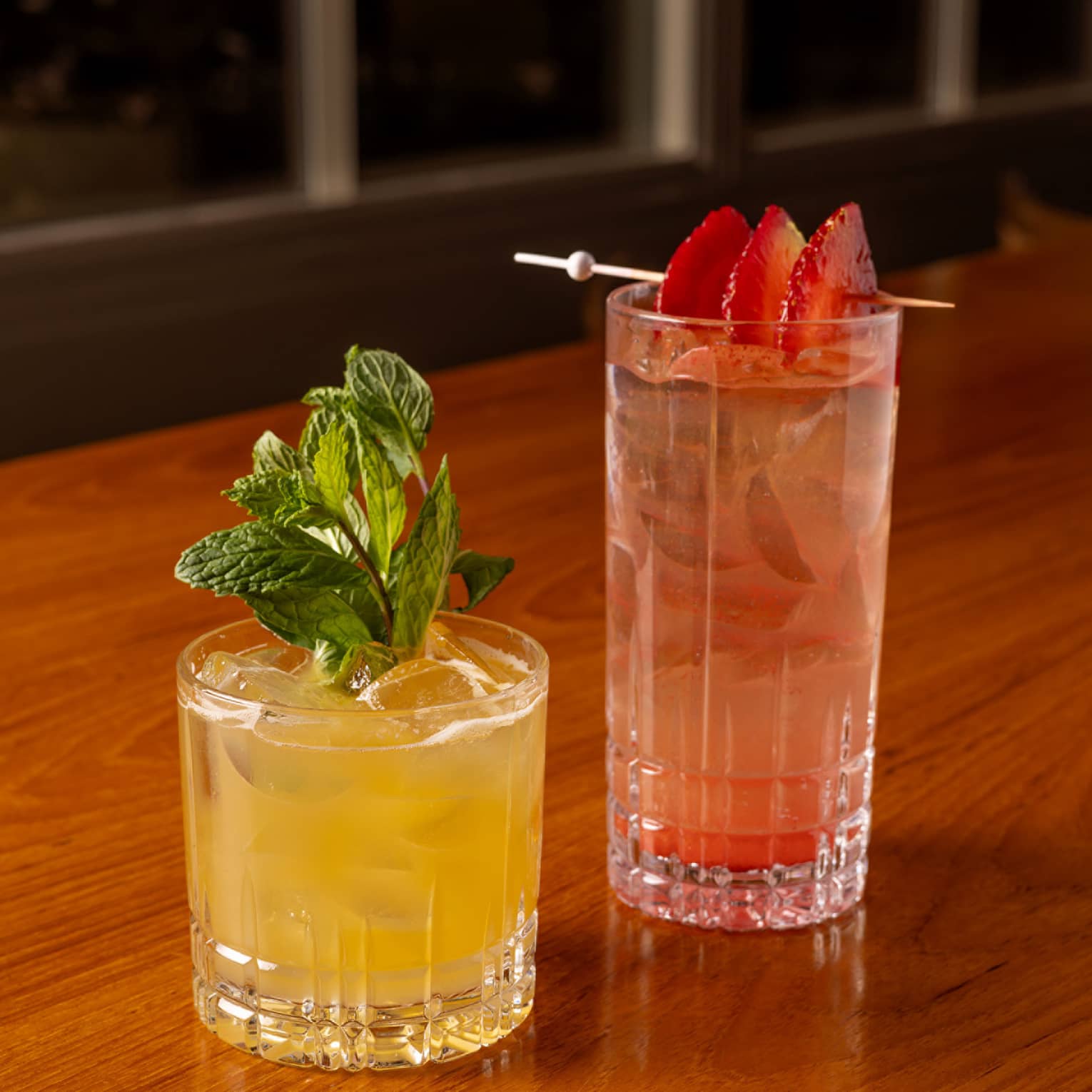 One yellow drink and one red drink placed beside each other on a dining table