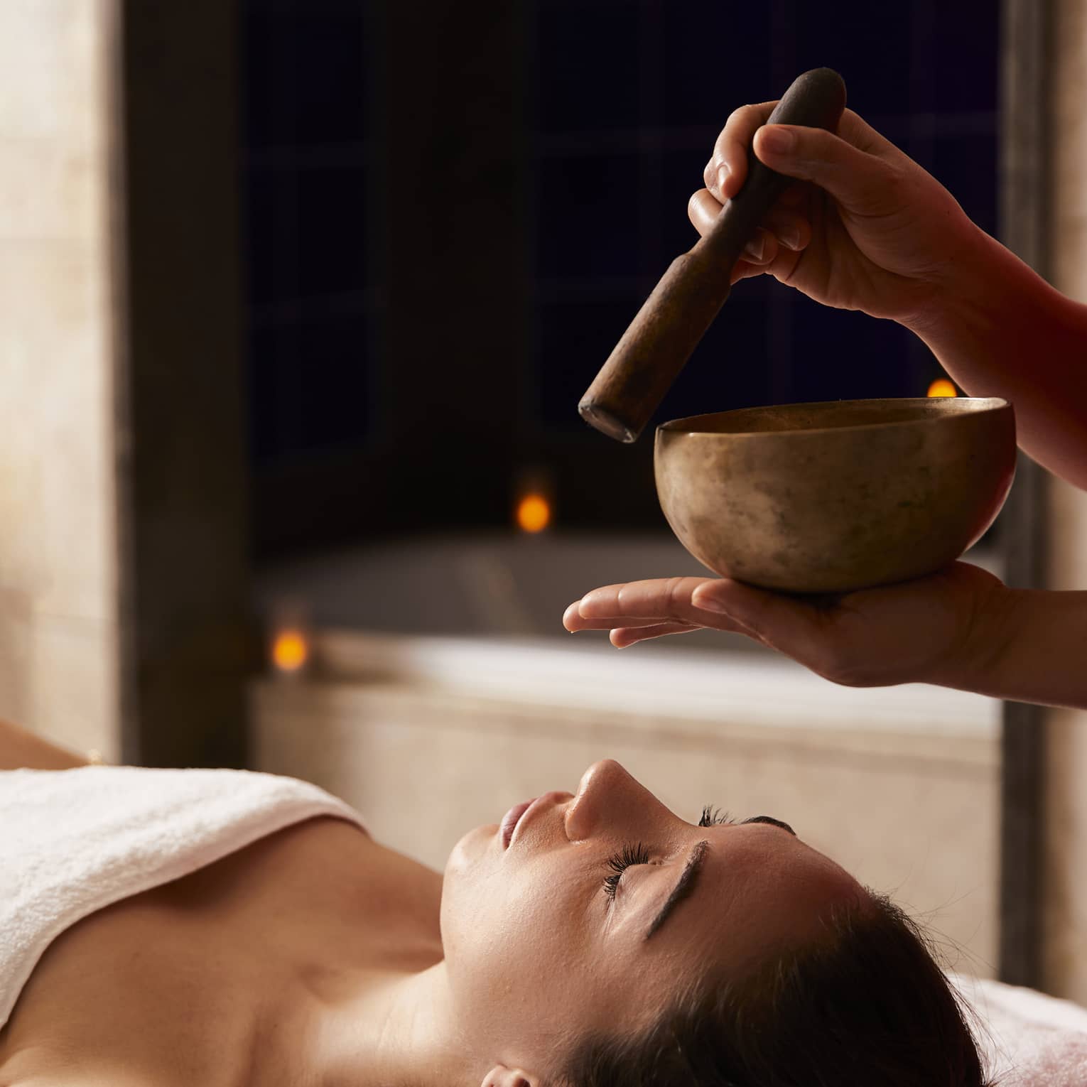 A woman receiving a spa treatment with bowls to create sounds.