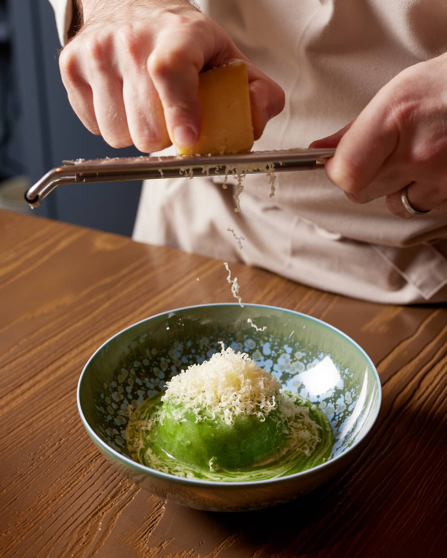 Chef grates Parmesan cheese over dish