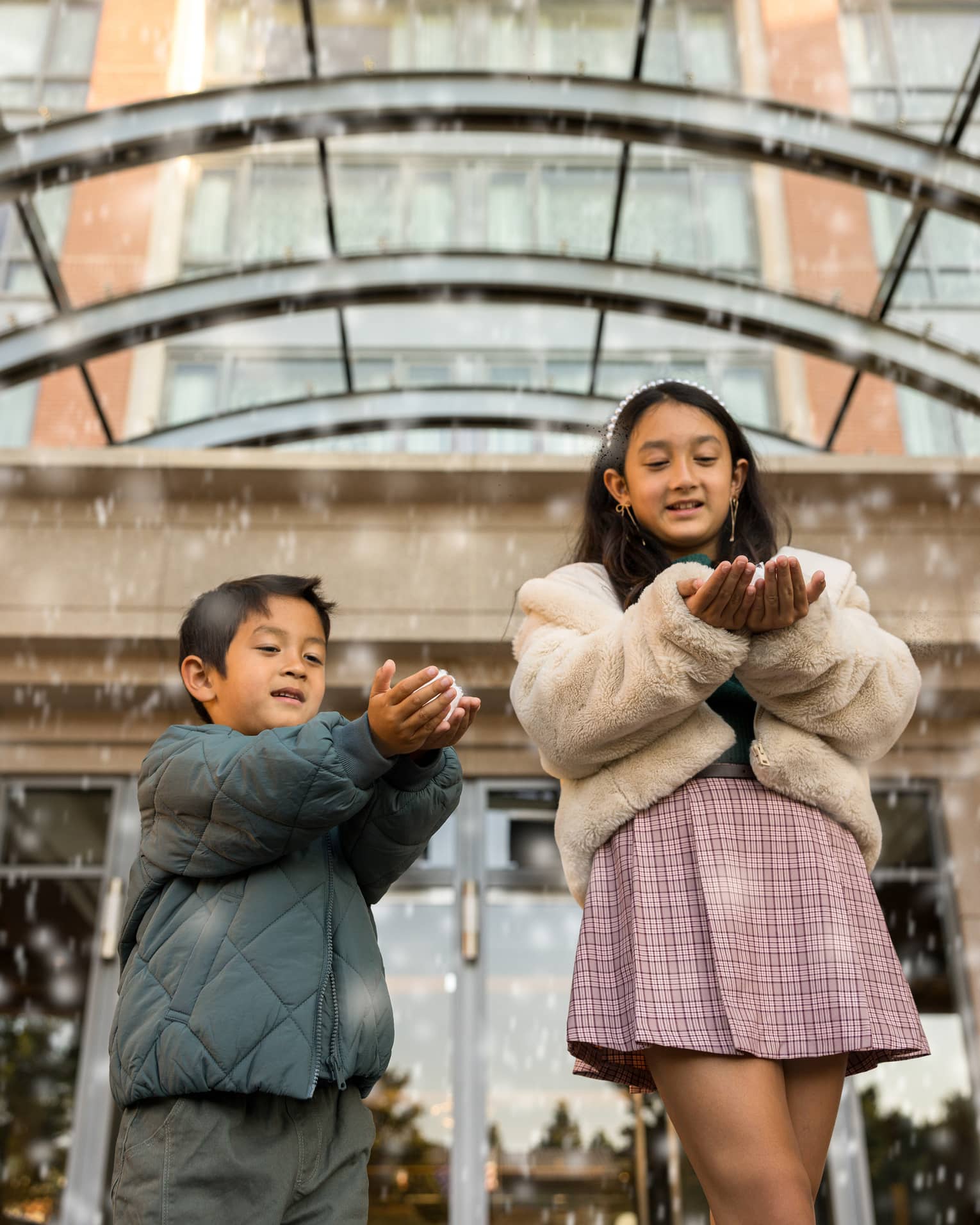 Two kids play with faux snow falling from the ceiling of a hotel entrance