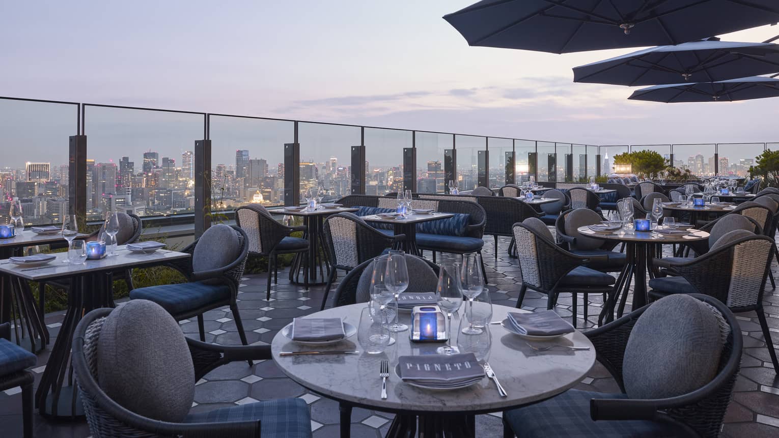 Pigneto Terraza rooftop patio dining tables at dusk, city view below