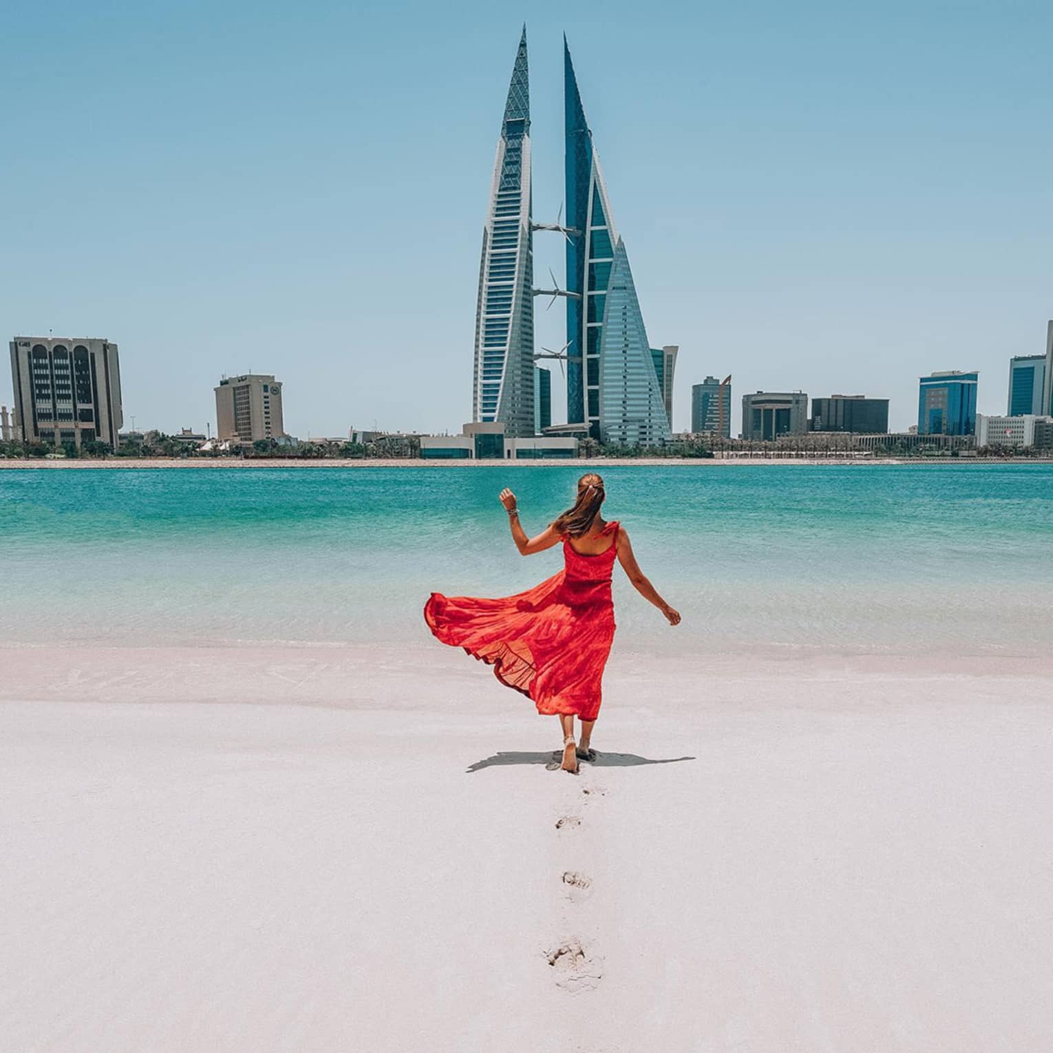 Woman on beach with bahrain city view