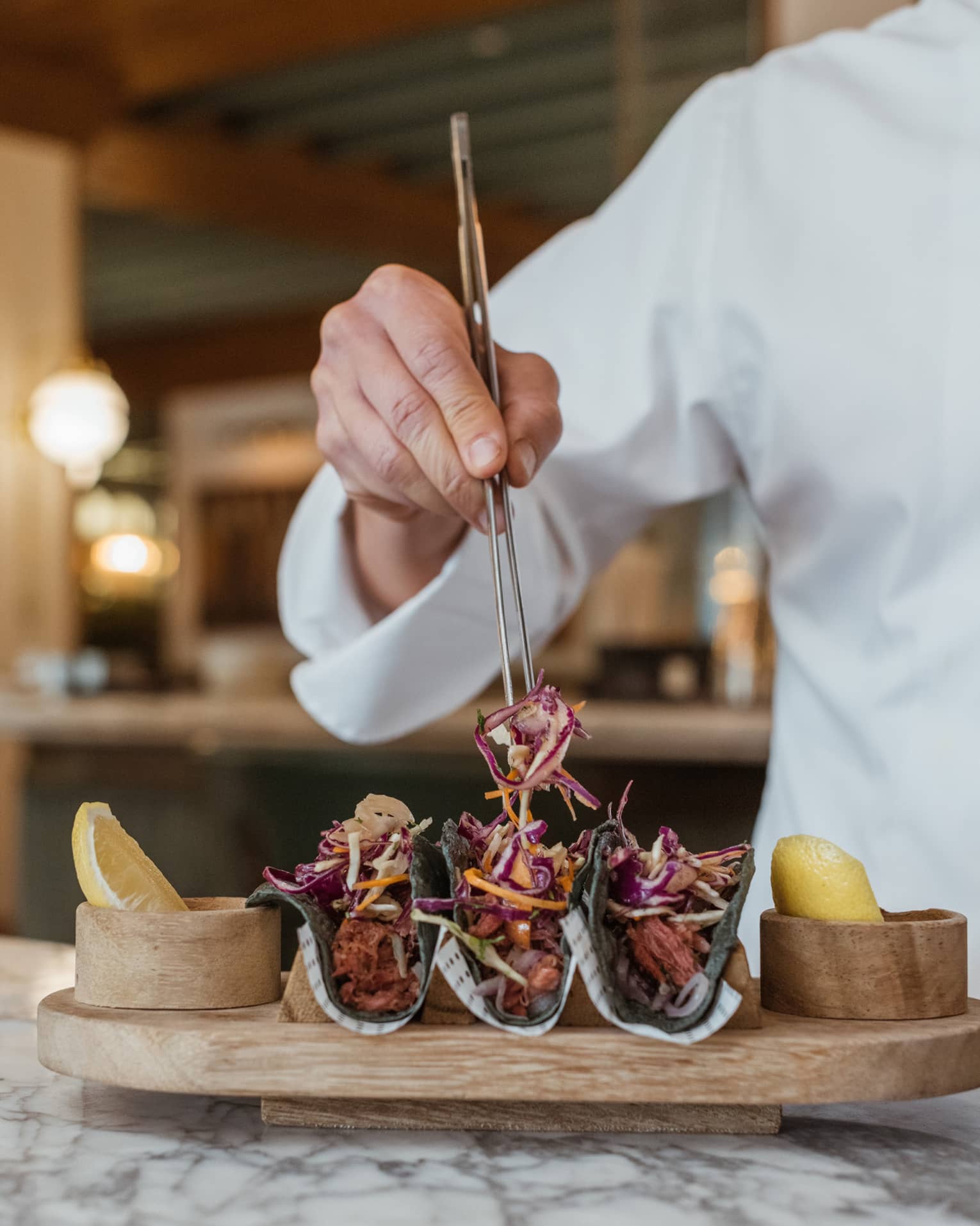 Chef arranging tacos on wooden platter