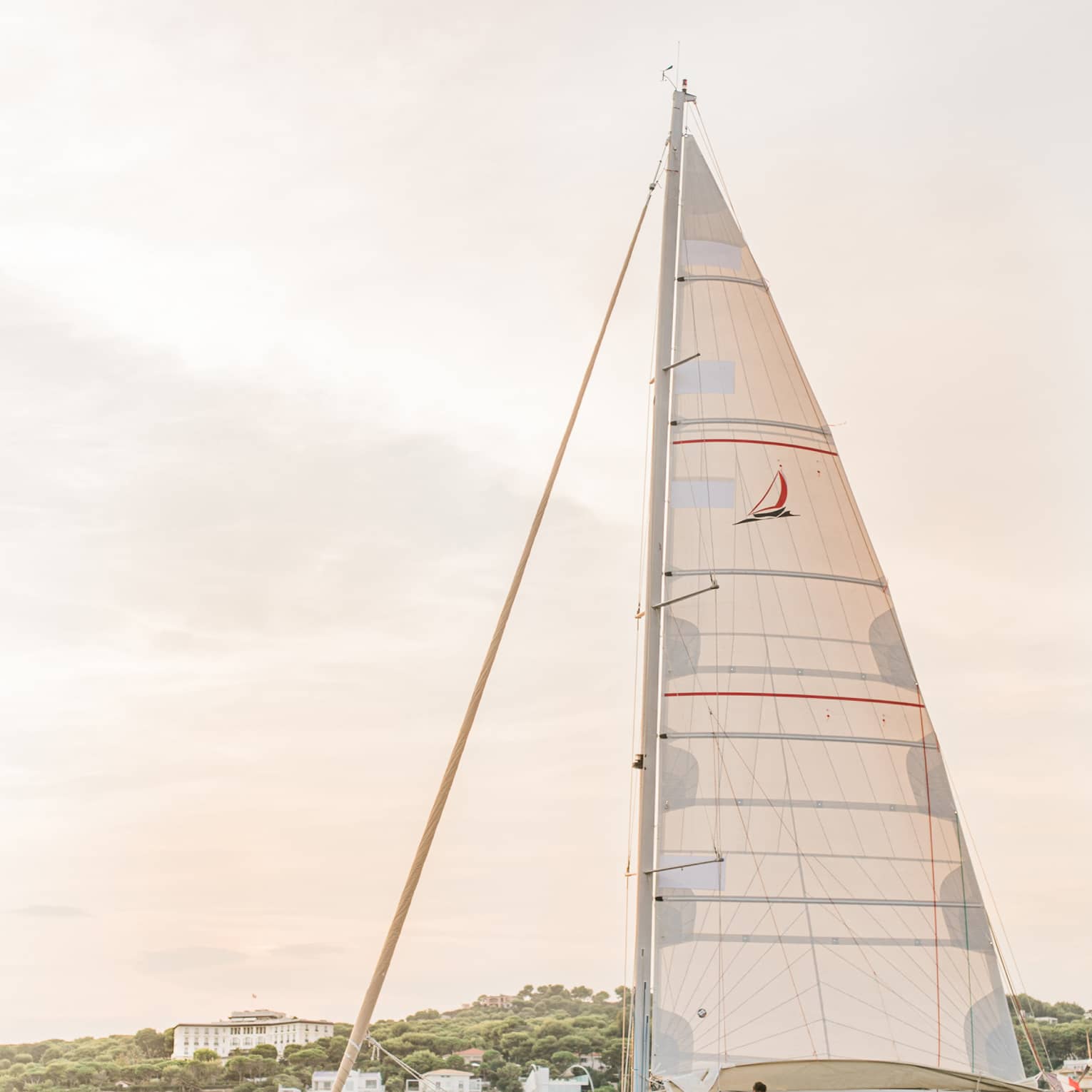White sailboat on water in front of island with white buildings
