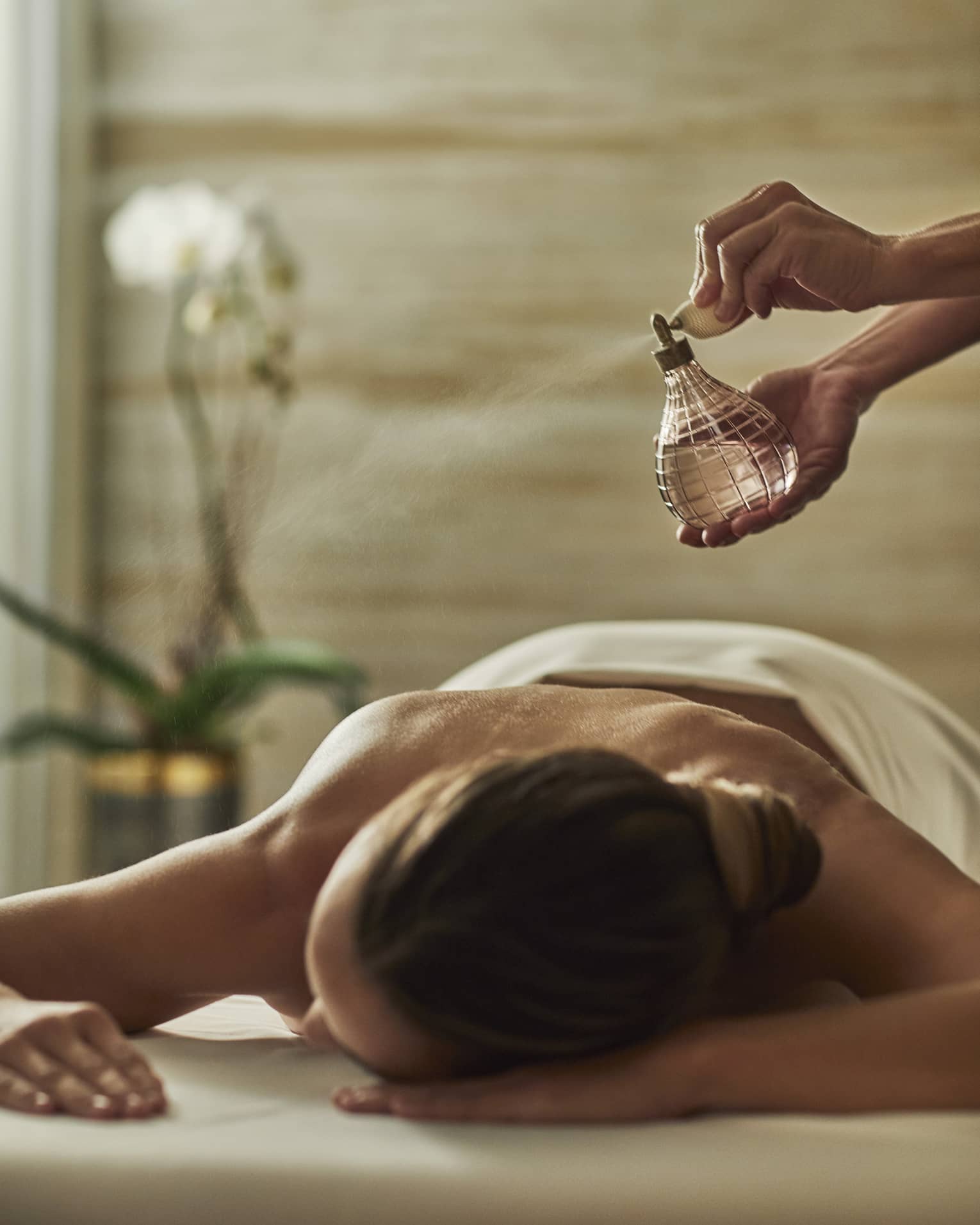 A woman having mist sprayed over her on a spa treatment room.