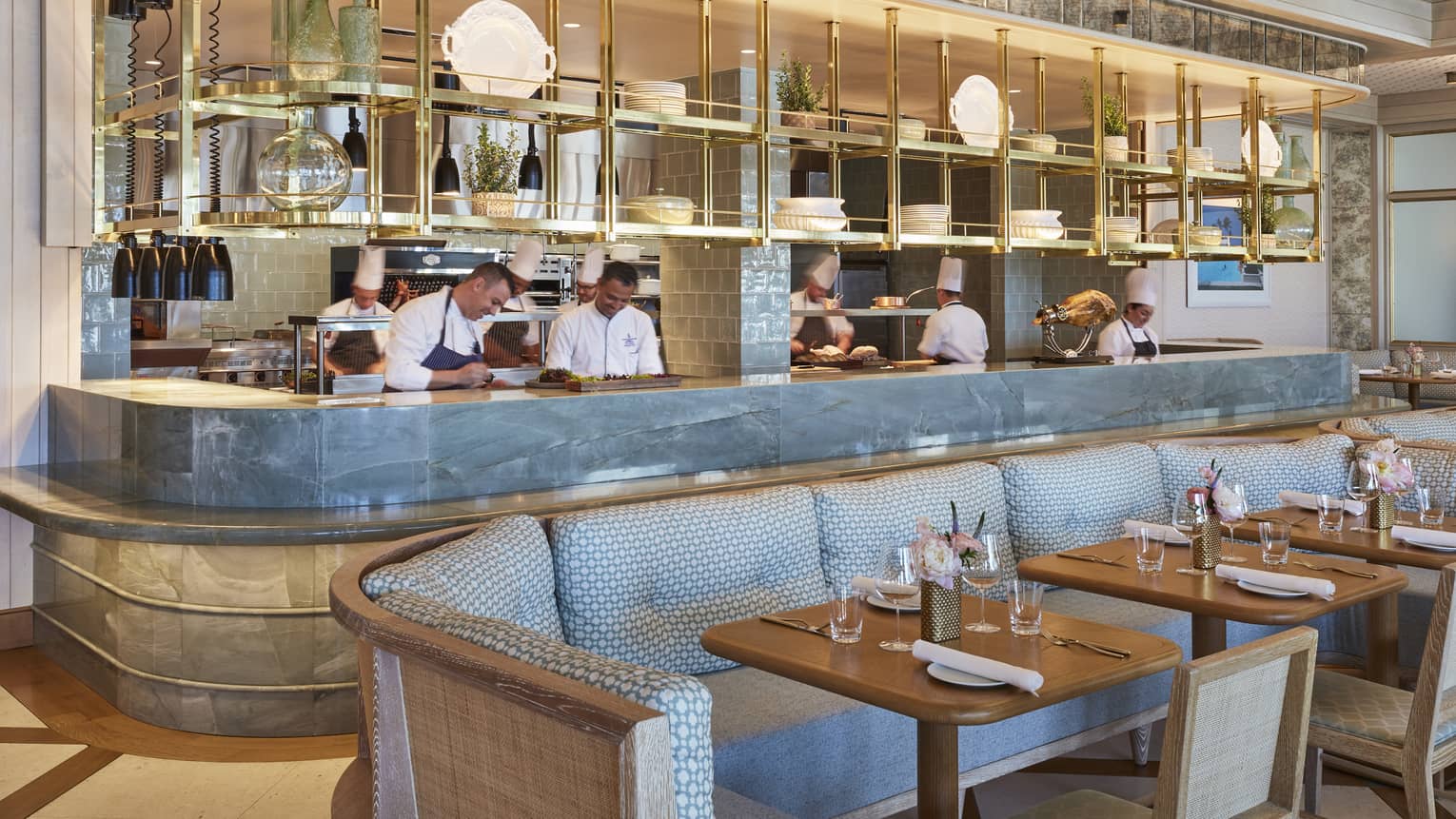 Staff members behind Flories curved blue marble bar, blue banquette seating
