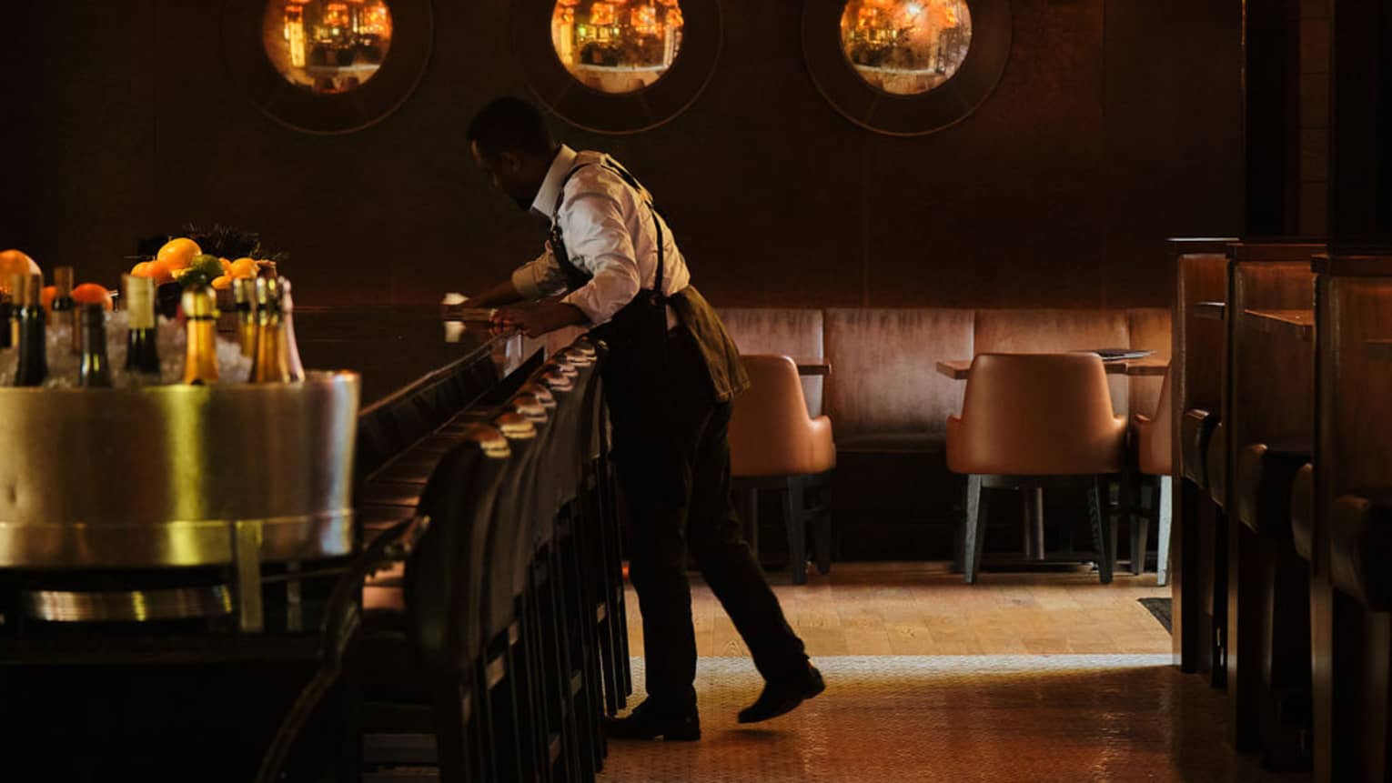 Glowing lights above the long black bar with stools