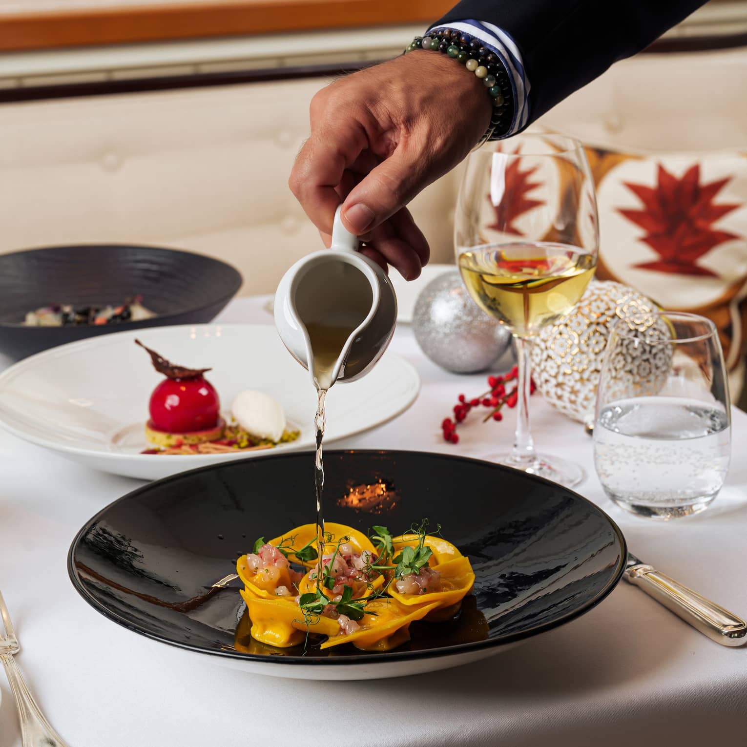 A sauce being poured onto food on a black plate.