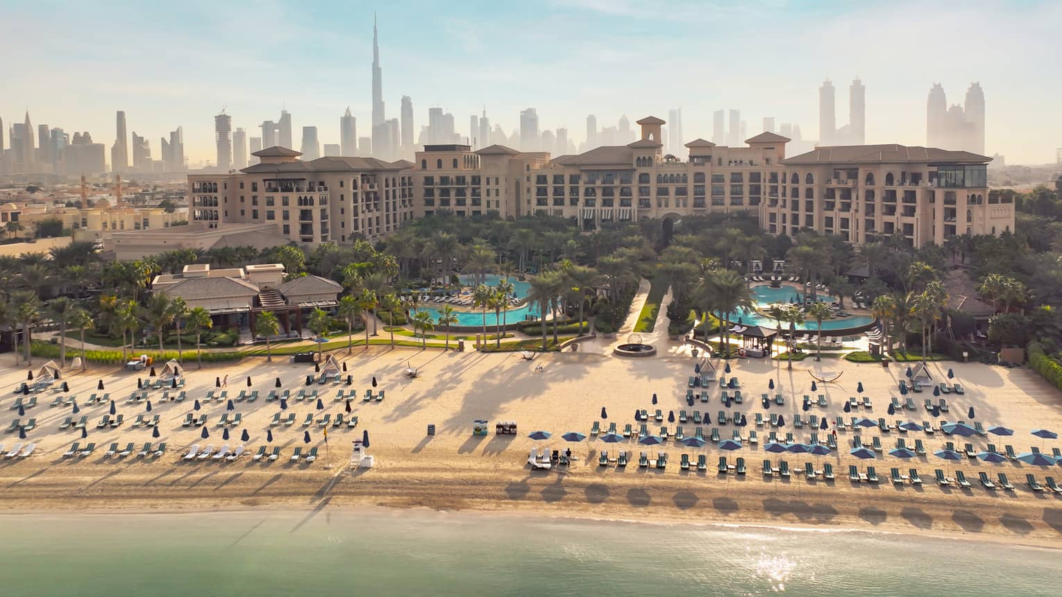 An overhead shot of a resort with lines of beach chairs in front of the bay.