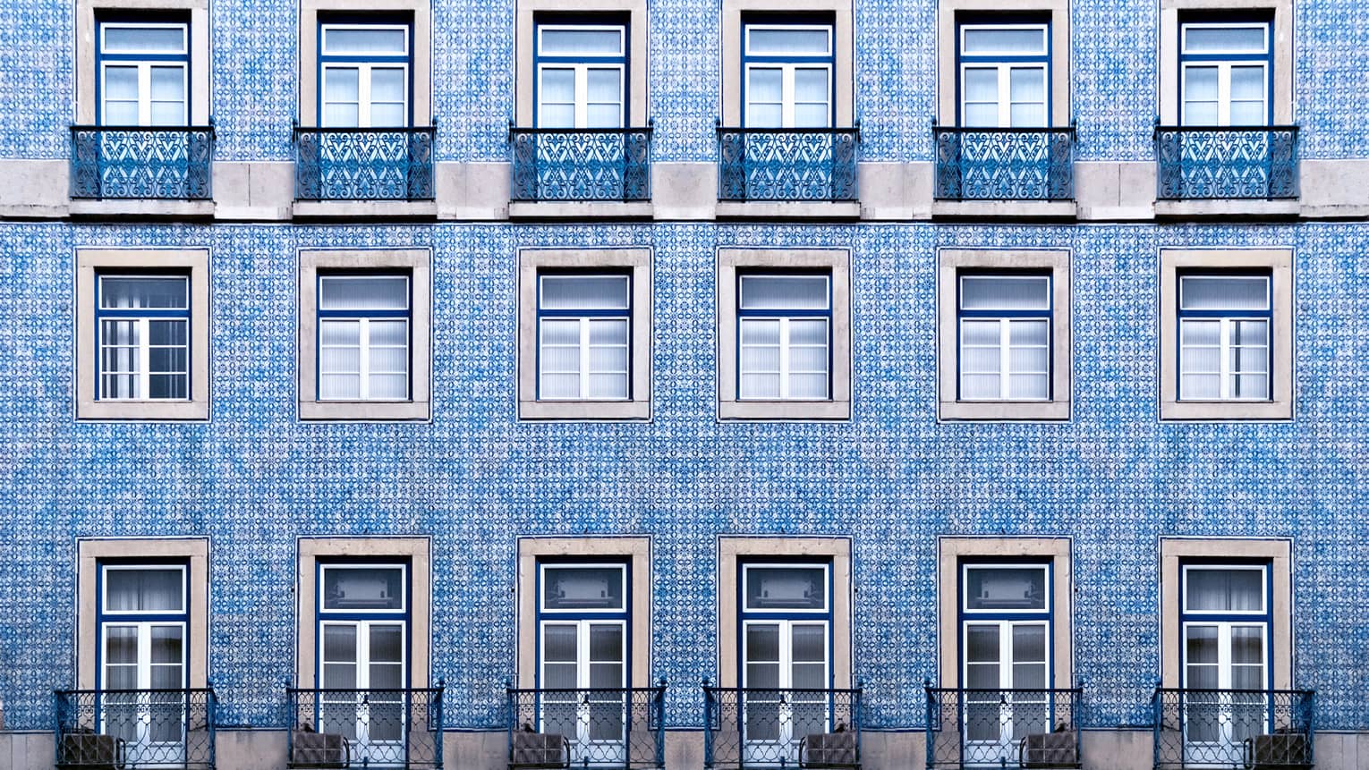 A blue tiled wall with many windows and balconies.