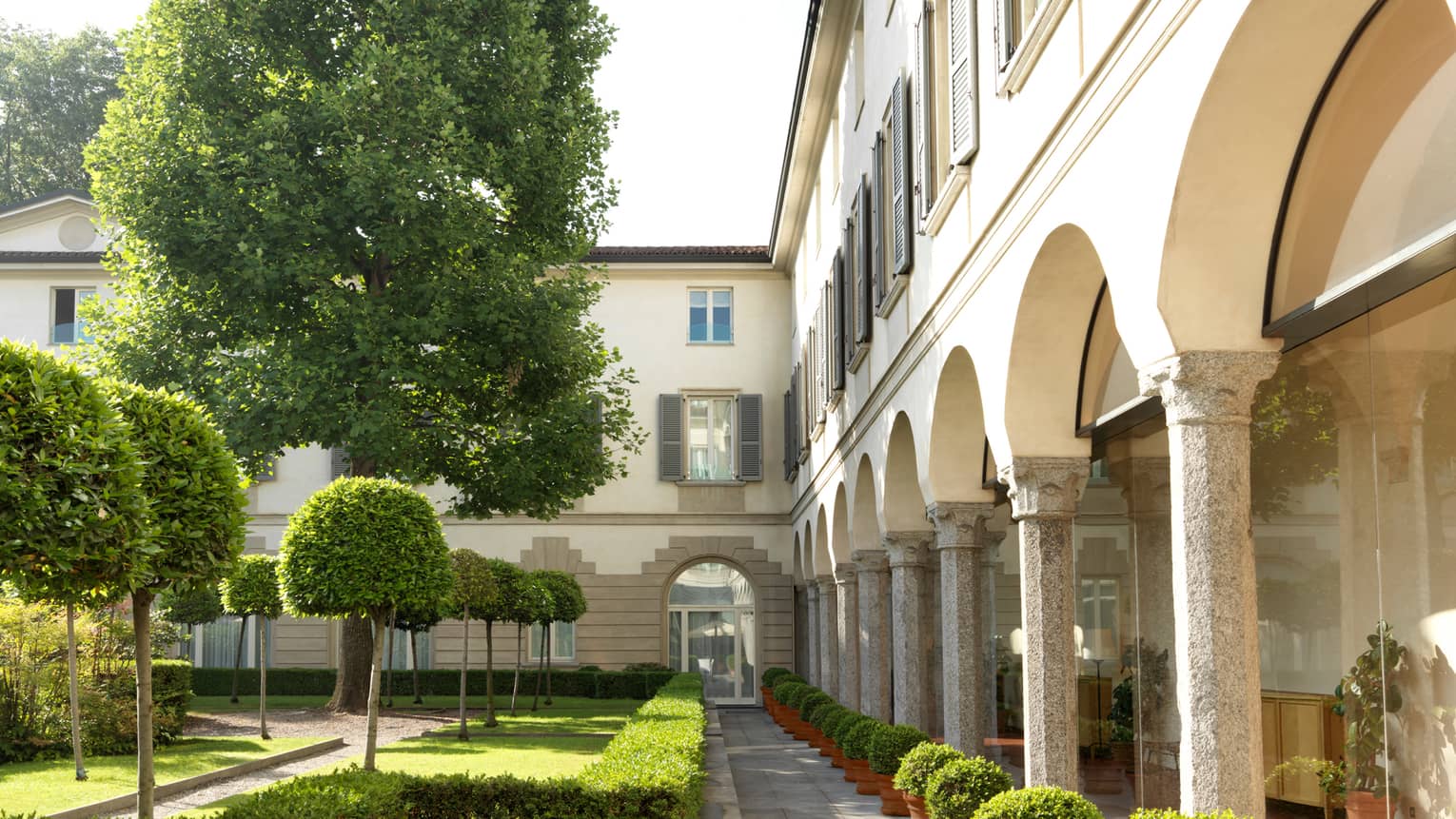 Historic 1990s photo of Four Seasons Hotel, pillars around courtyard with shrubs, trees