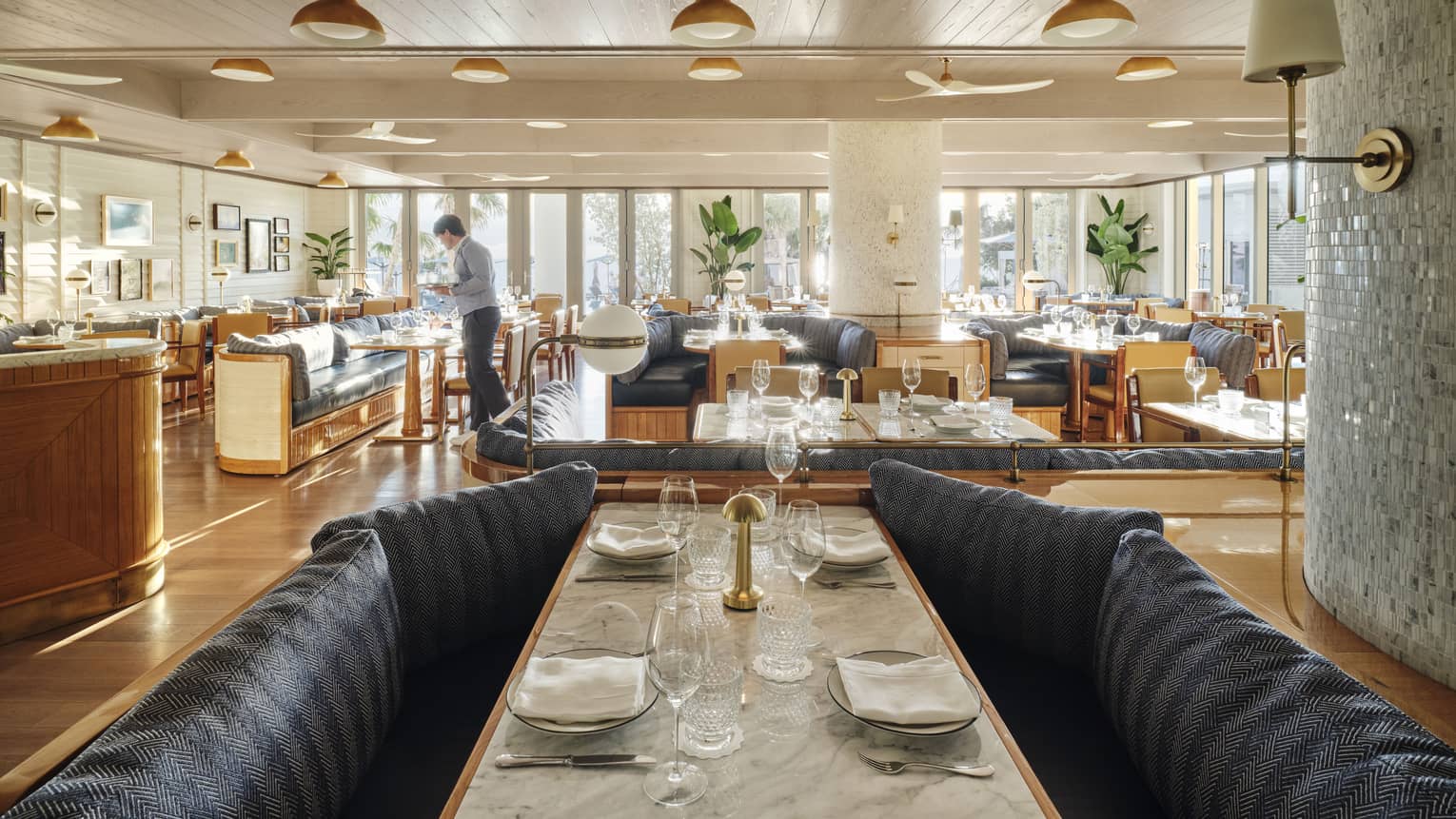 A brightly lit dining outlet with large booths, large tables and large windows.