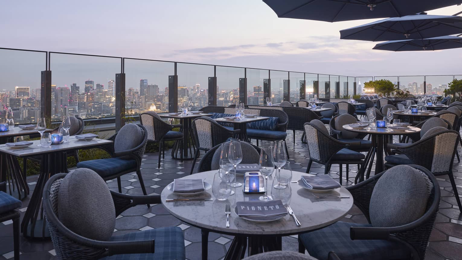 Pigneto Terraza rooftop patio dining tables at dusk, city view below