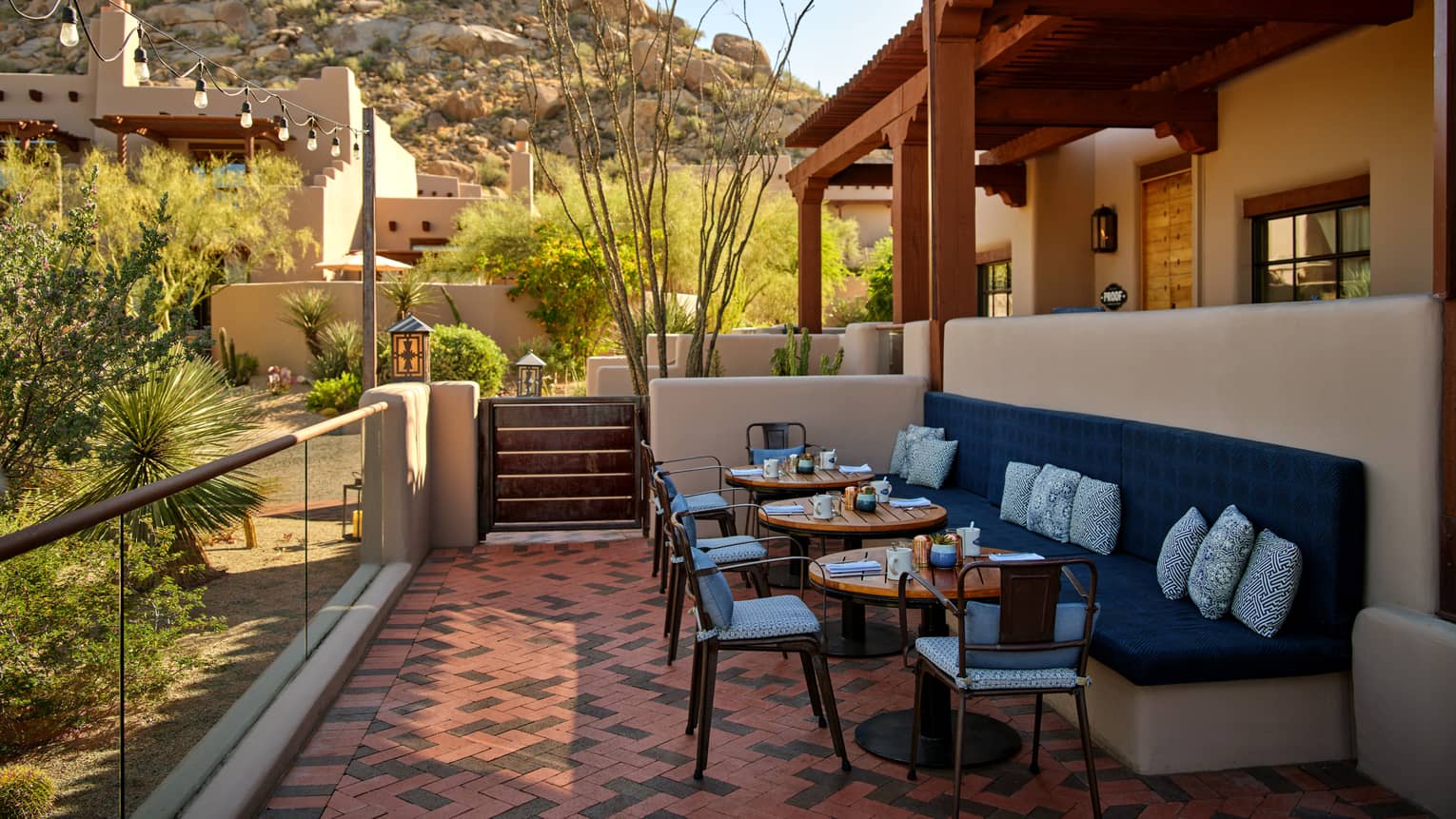 Outdoor terrace with booth seating and chairs and a view of the mountains.