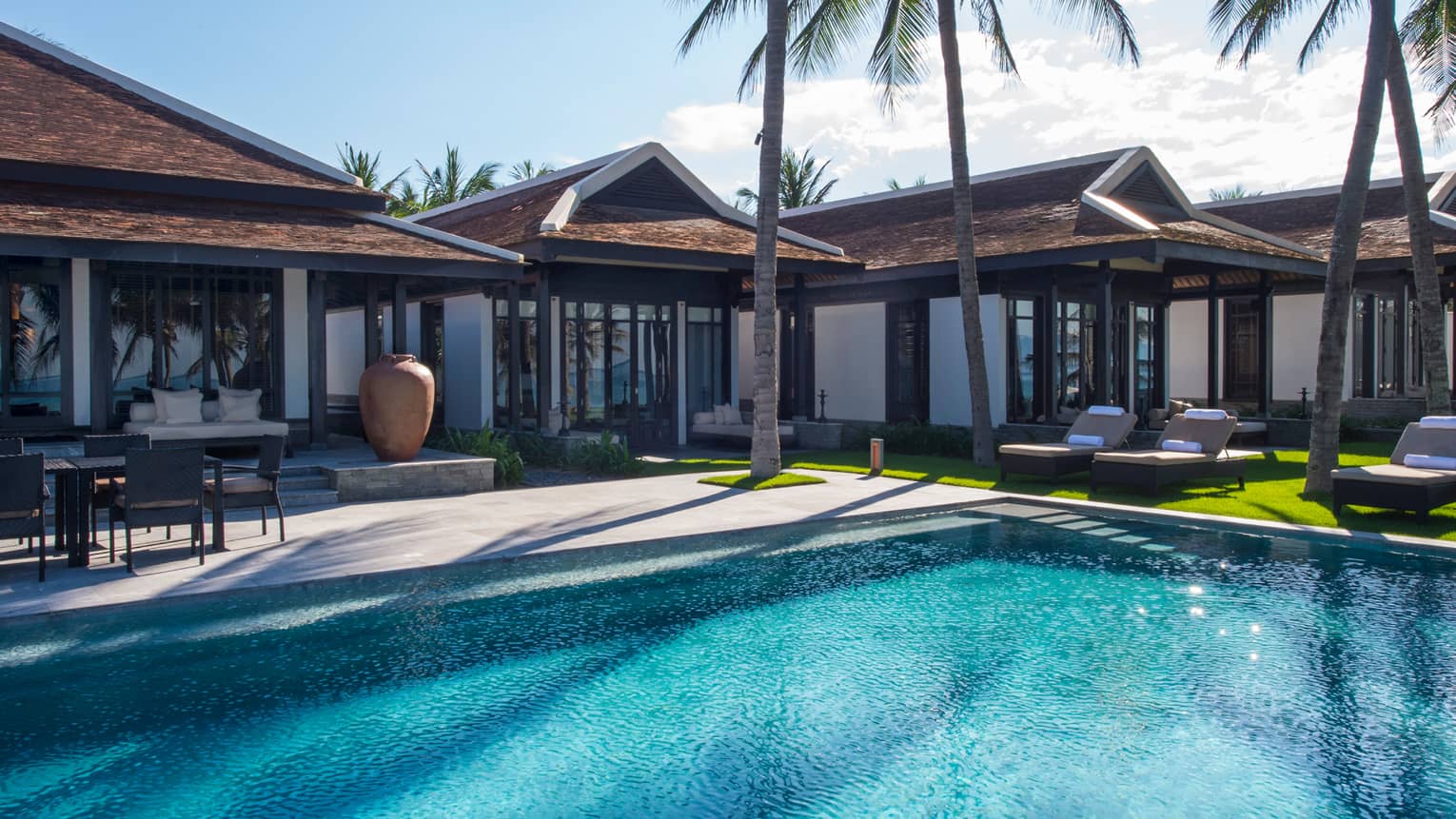Five bedroom pool villa exterior. tall palm trees around outdoor swimming pool