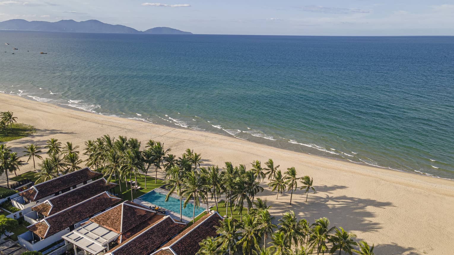 5 Bedroom Beachfront Pool Villa aerial shot with ocean and mountain views, palm trees and blue skies