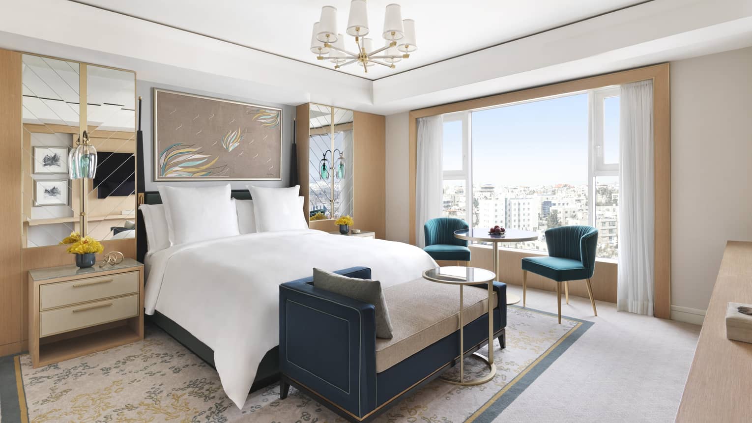 A bed in the centre of a cream coloured room with a chaise perched at the end of the bed. 