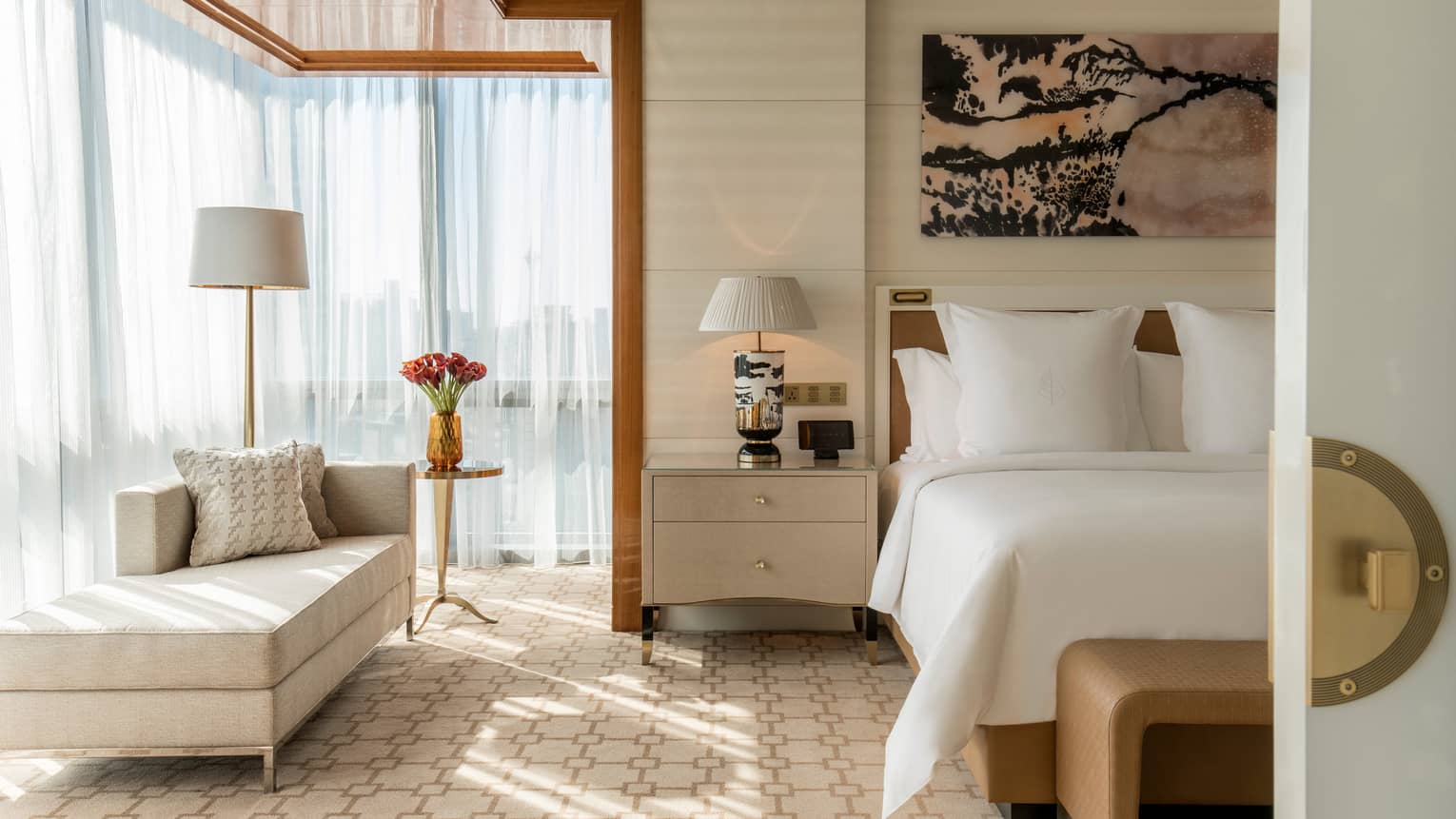White bed under modern pink-and-black art, corner window with sheer curtains, chaise