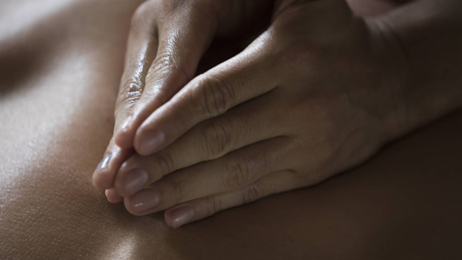 Two hands massage a person's back