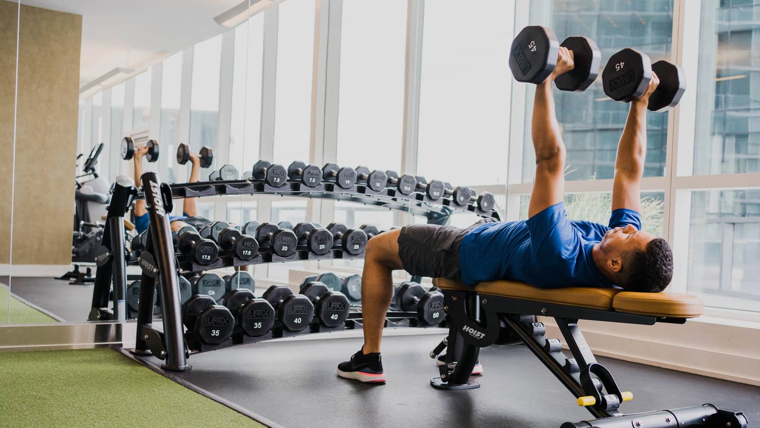 A man lifting two weight while laying on a bench.