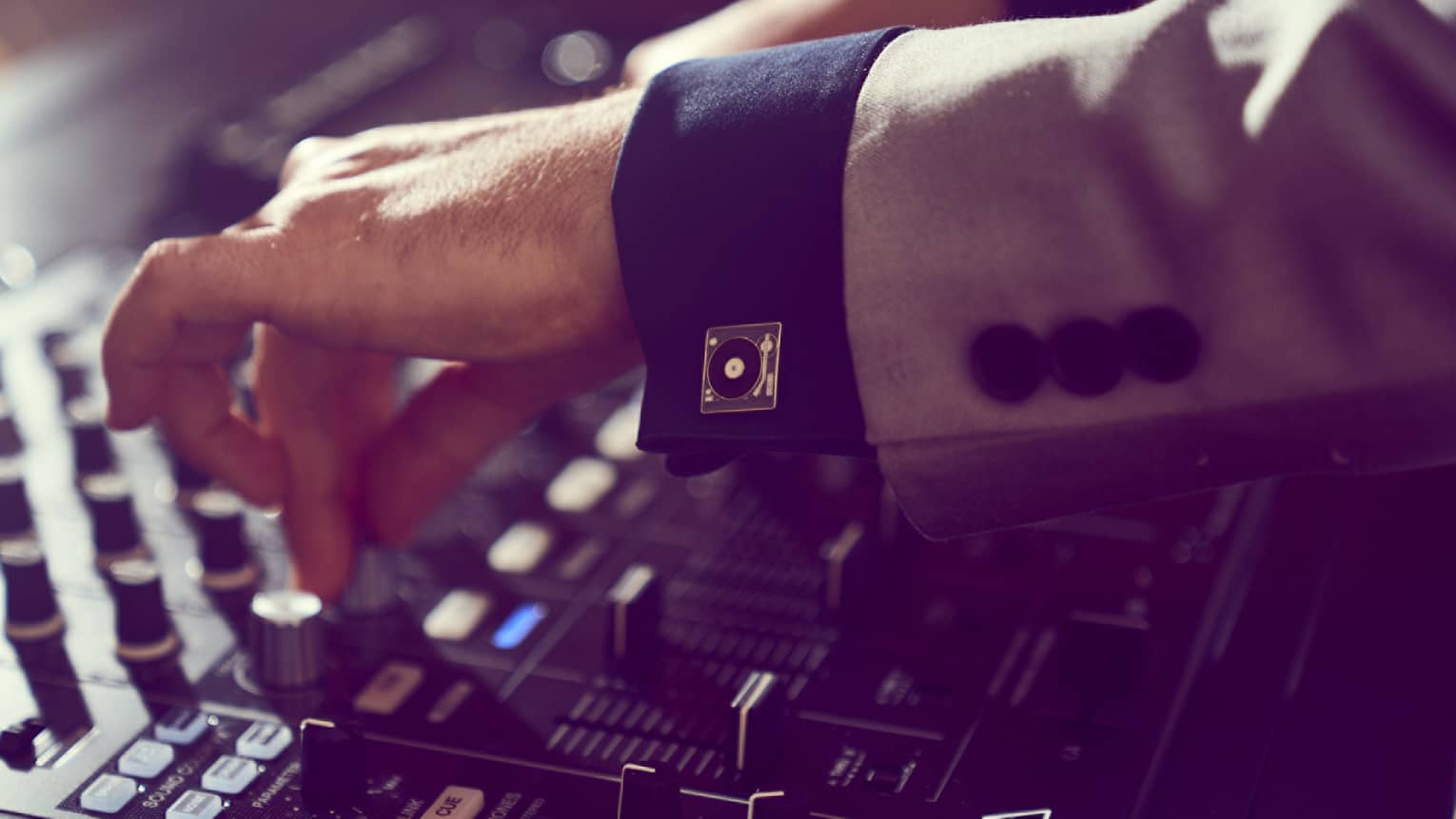 Close up of a DJ's hands turning knobs on a soundboard