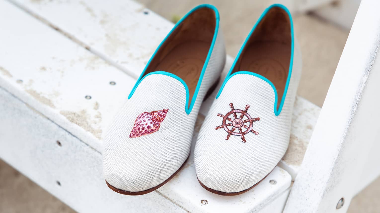 Stubbs & Wootton loafers with nautical embroidery placed on a white wooden step