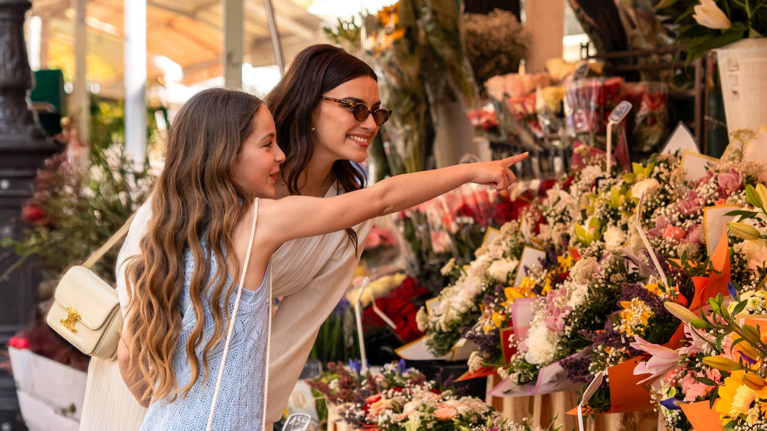 Two guests standing near a display of flowers at an outdoor shop