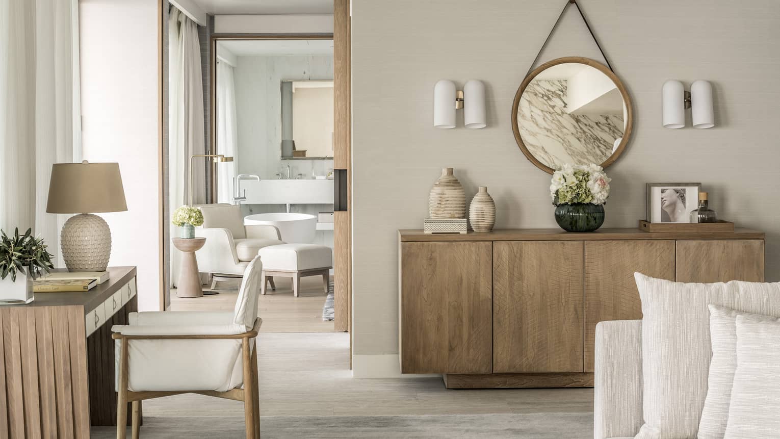 Arion Sea View Suite with white sofa, blonde wood sideboard and matching desk, doorway to bathroom