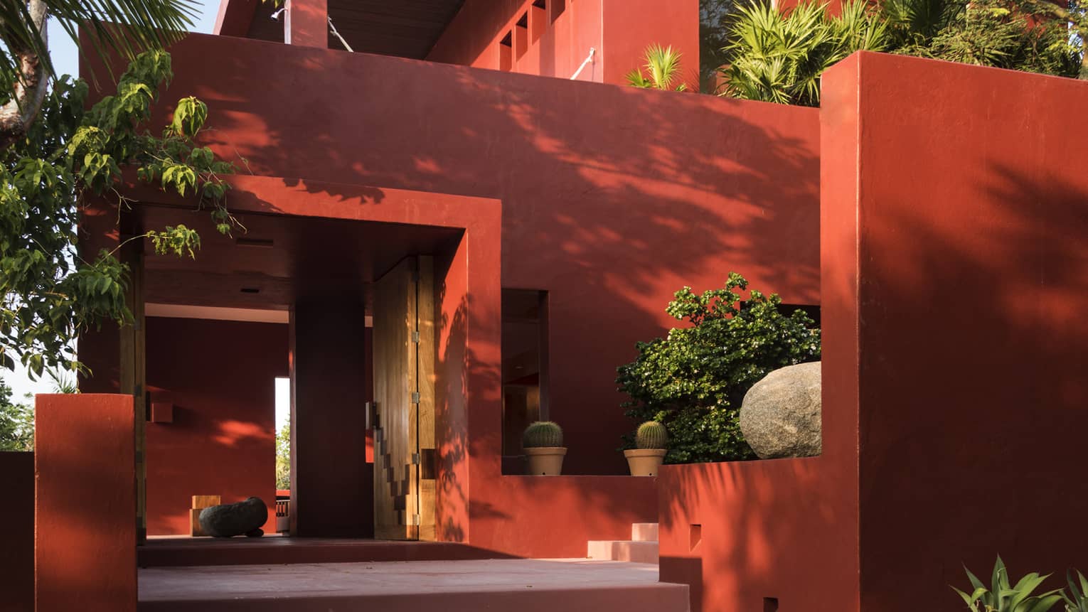 Stairs to entrance of of red stucco private villa with trees