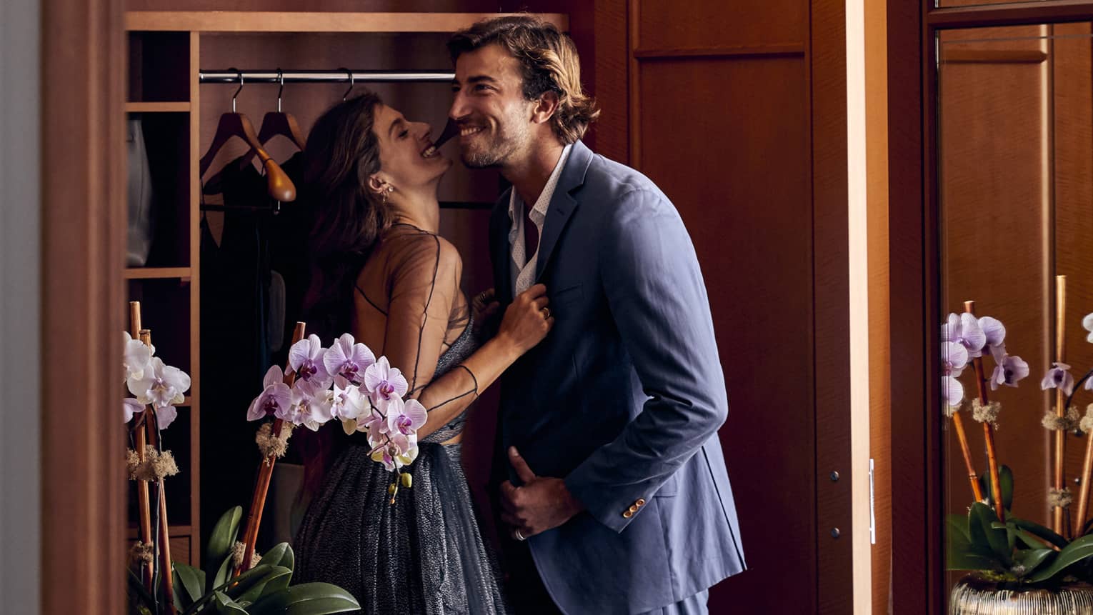Man and woman smile next to closet in hotel room