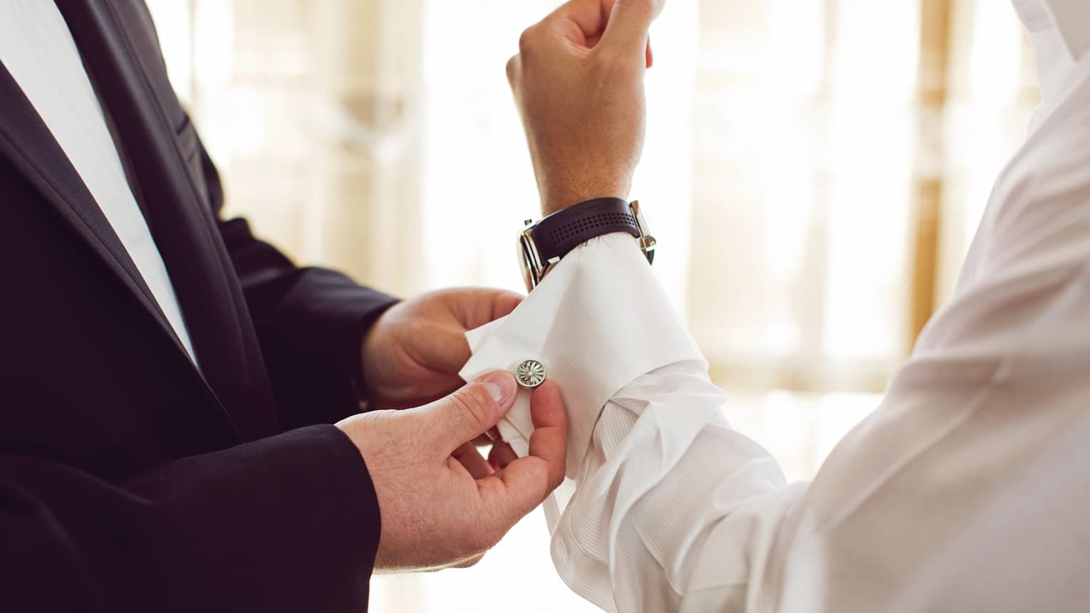Close-up of hotel staff assisting man button suit shirt sleeve cuff