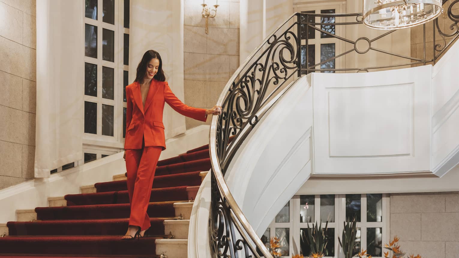 A woman in a red suit walking down stairs.