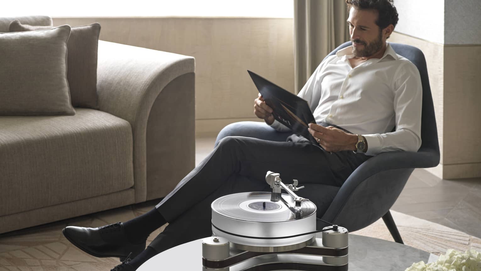Man lounges in armchair with folder in guest room