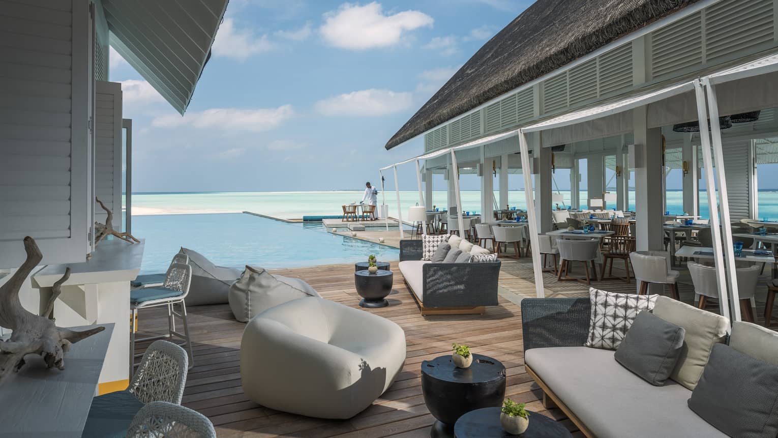 Couches and chairs arranged by a pool overlooking the ocean at the Blu Beach Club