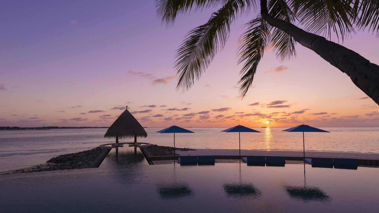 Sunset view of outdoor infinity pool near the beach 