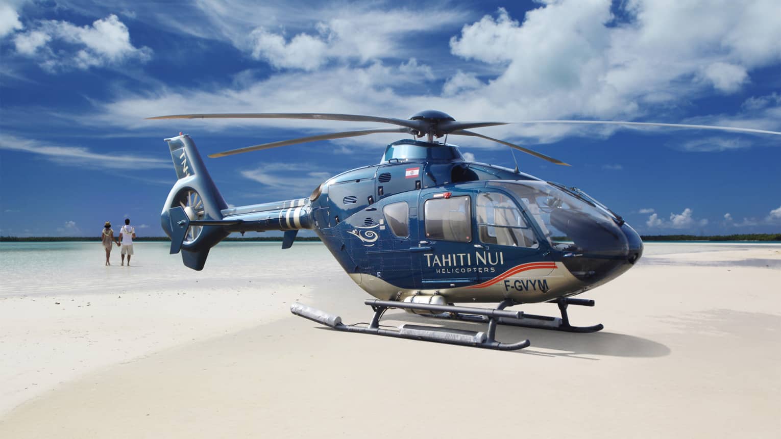 Guests walk on the beach before boarding the Tahiti Nui Helicopter for an island tour